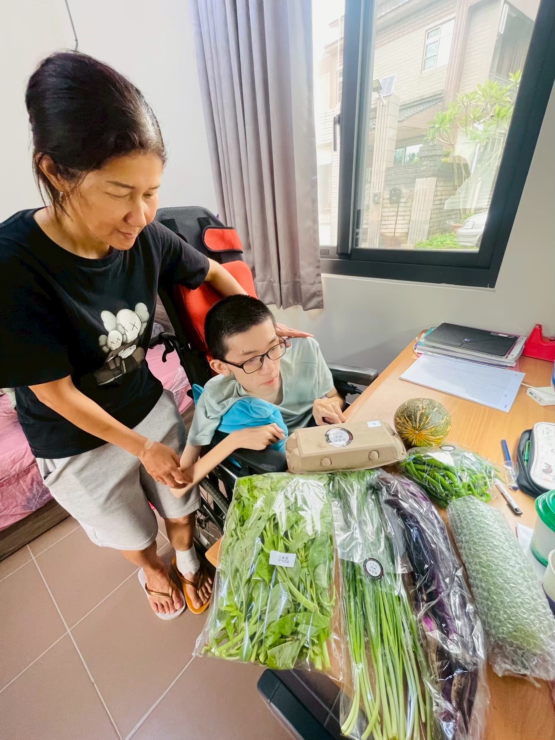 健安和媽媽接收展望會發放的蔬菜箱感謝大家的善心。